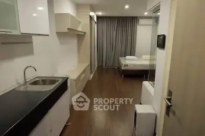 Modern studio apartment with sleek kitchen and cozy sleeping area, perfect for urban living.