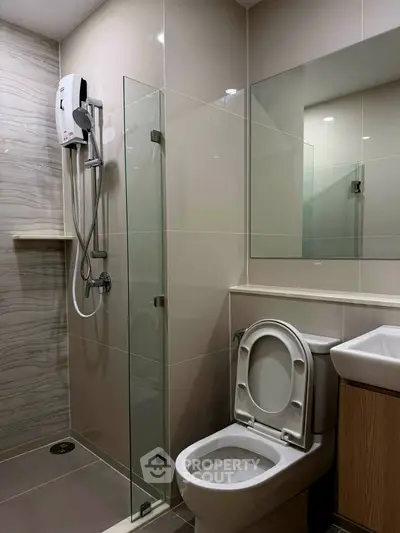 Modern bathroom with glass shower and sleek fixtures in contemporary apartment.