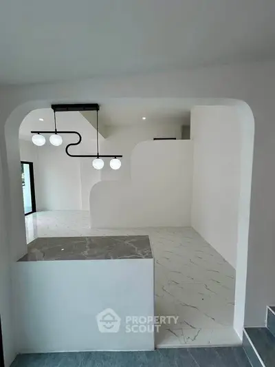 Modern minimalist interior with sleek white walls and unique lighting fixtures, showcasing contemporary design.