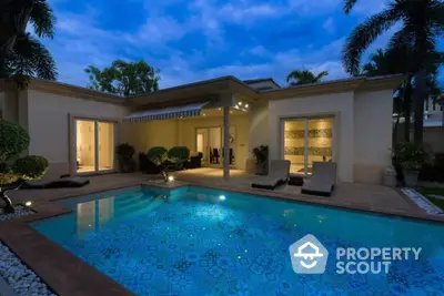 Luxurious villa with a stunning illuminated pool and elegant patio, perfect for evening relaxation and entertainment.