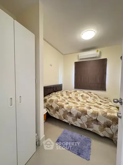 Cozy bedroom with modern decor and ample natural light, featuring a comfortable bed and sleek wardrobe.