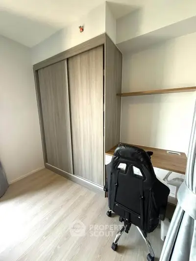 Modern study room with sleek desk and ergonomic chair, featuring built-in wardrobe and light wood flooring.