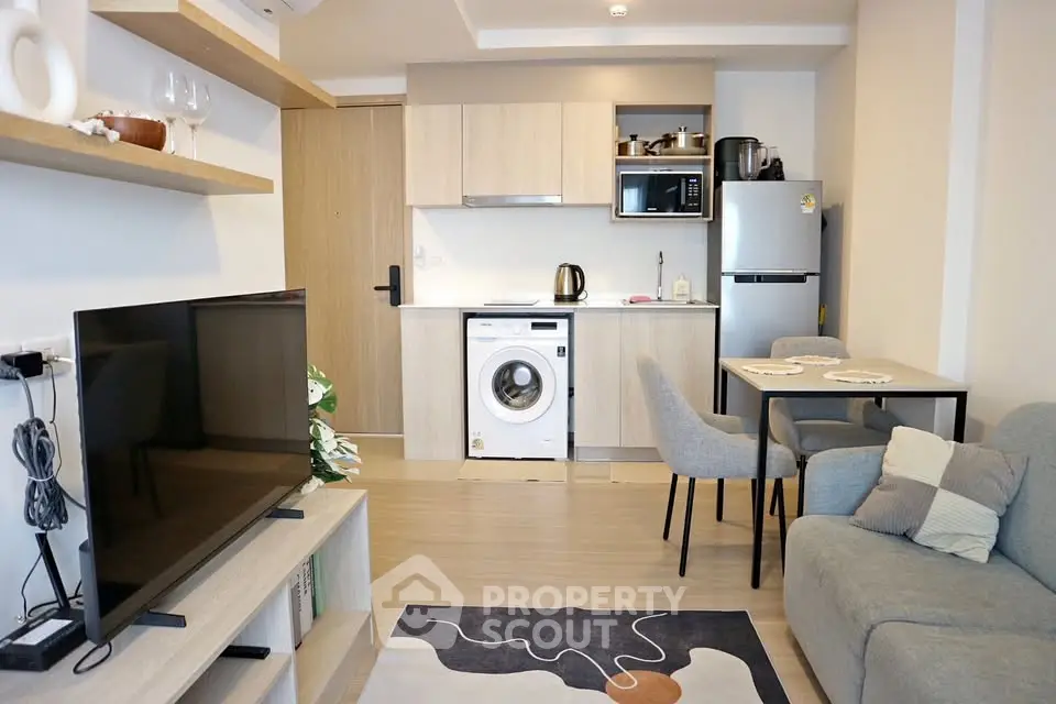 Modern open-plan living room with kitchen, featuring sleek appliances and cozy seating area.