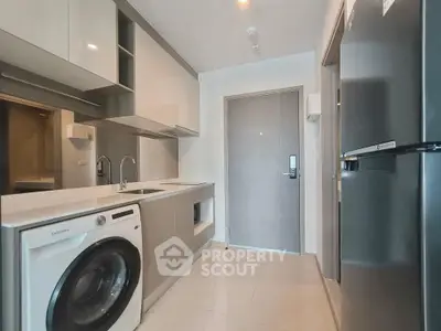 Modern kitchen with sleek appliances and washing machine in compact layout