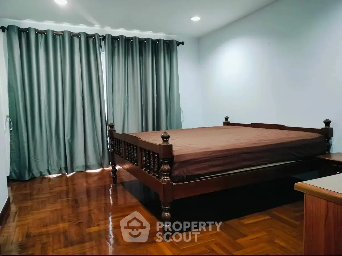Spacious bedroom with elegant wooden bed and polished hardwood floors