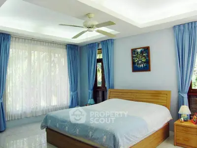 Spacious bedroom with large windows and elegant blue curtains