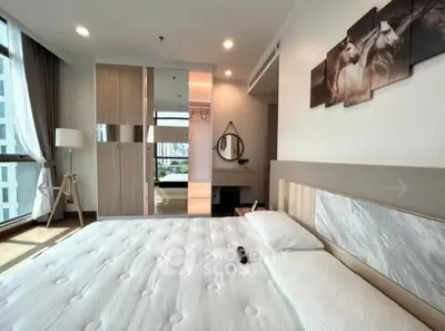 Spacious modern bedroom with large windows and stylish decor in a high-rise apartment.