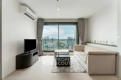 Modern living room with city view, featuring sleek furniture and large window.