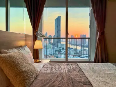 Luxurious bedroom with stunning city skyline and sunset view from large window.