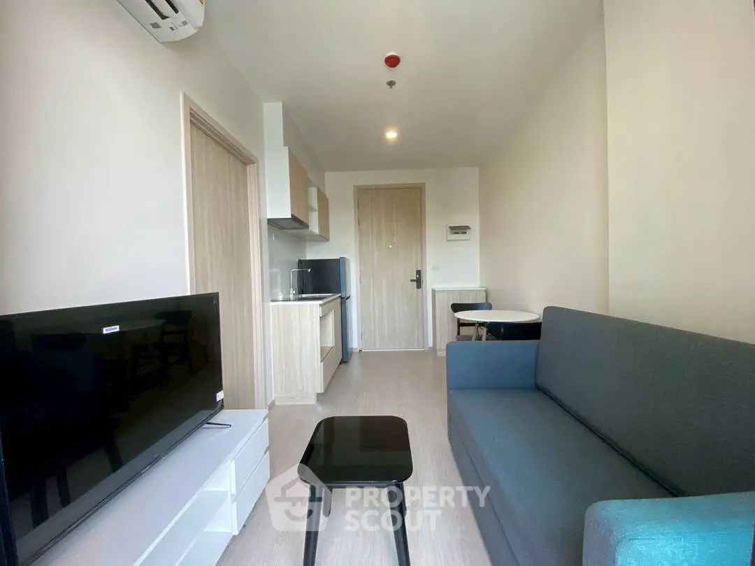 Modern living room with sleek furniture and compact kitchen in a cozy apartment.