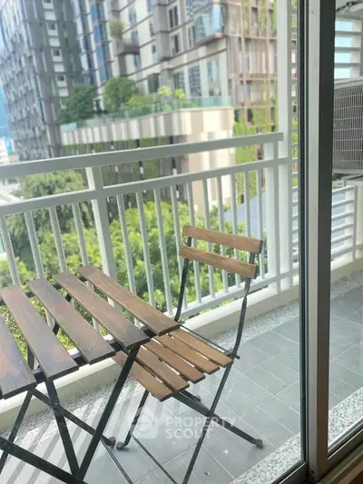 Charming balcony with outdoor seating and lush green view in modern apartment complex.