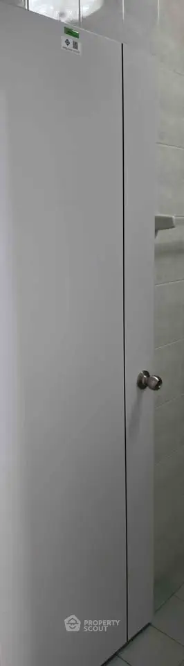 Modern bathroom with sleek white door and chrome handle, showcasing minimalist design.