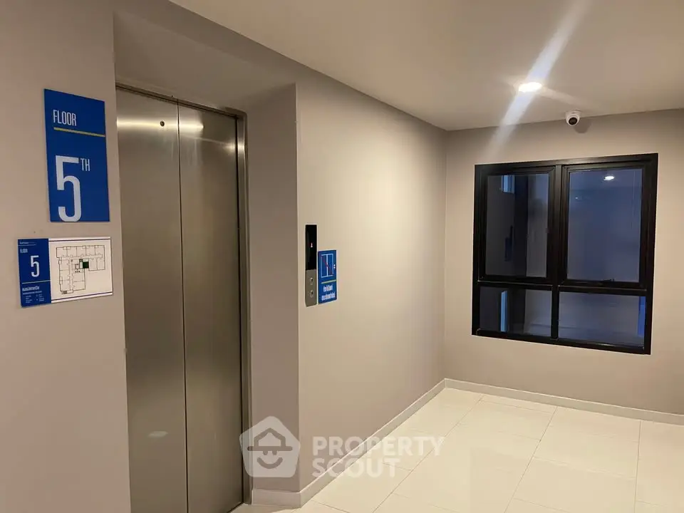 Modern elevator lobby on the 5th floor with sleek design and security camera.