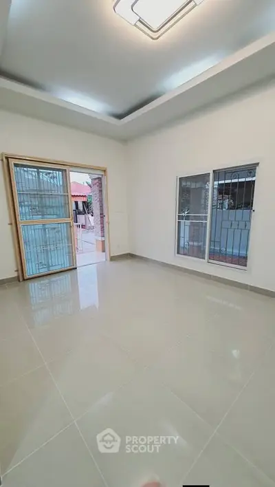 Spacious living room with large windows and tiled flooring