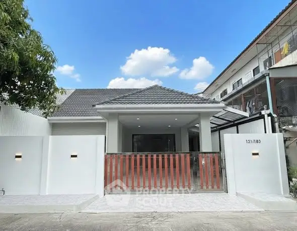 Charming single-story home with modern facade and gated entrance under a clear blue sky.