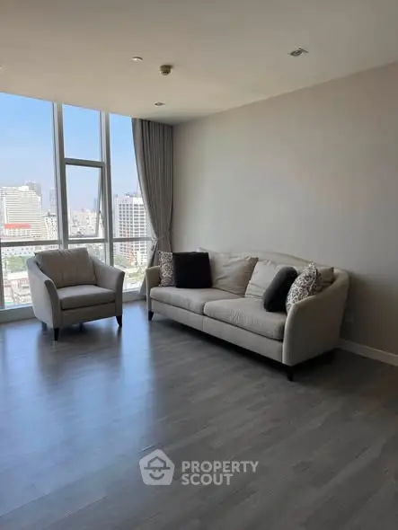 Spacious living room with modern furniture and city view through large windows.