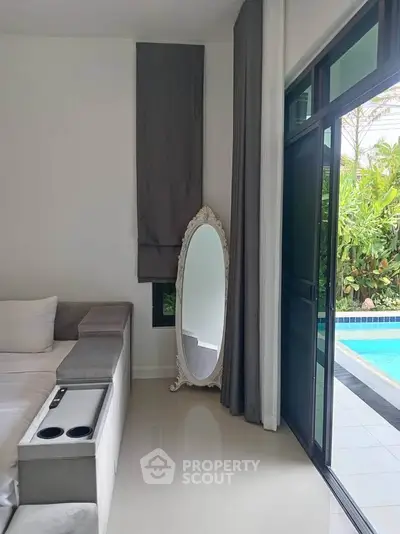 Luxurious bedroom with poolside view and elegant decor, featuring a stylish mirror and plush seating.