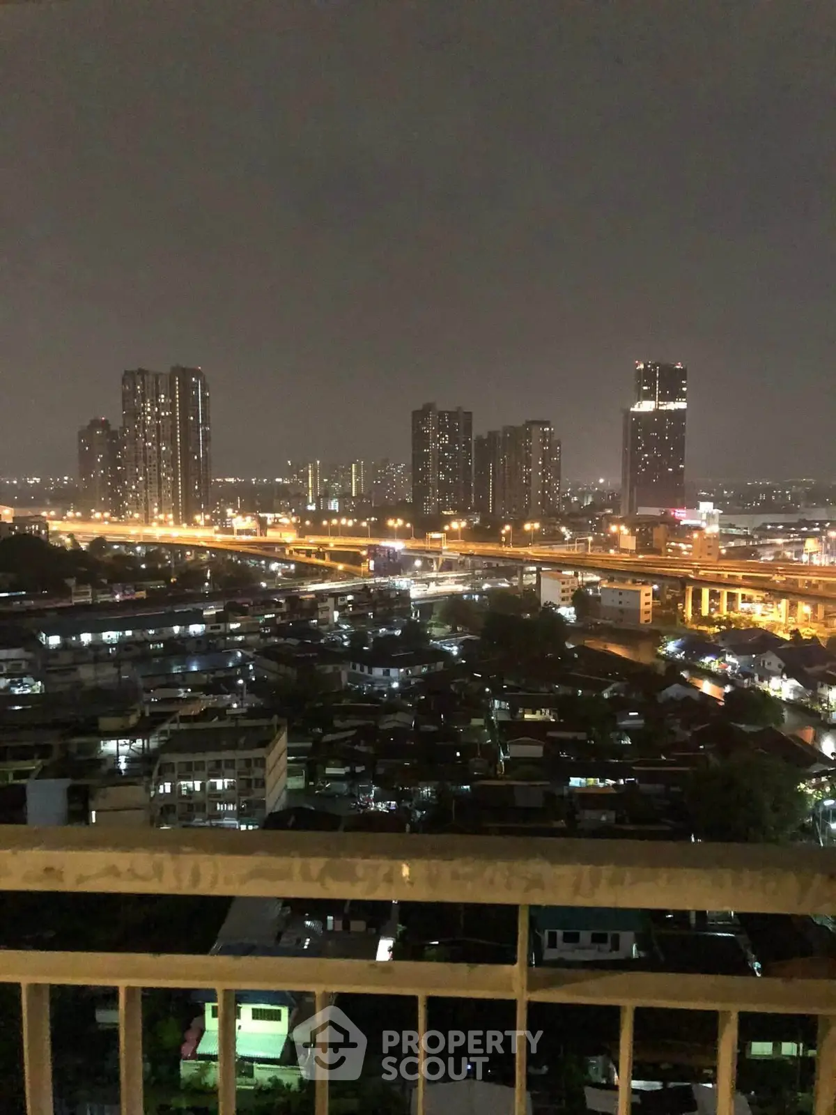 Stunning cityscape view from a high-rise balcony at night, showcasing urban skyline and twinkling lights.