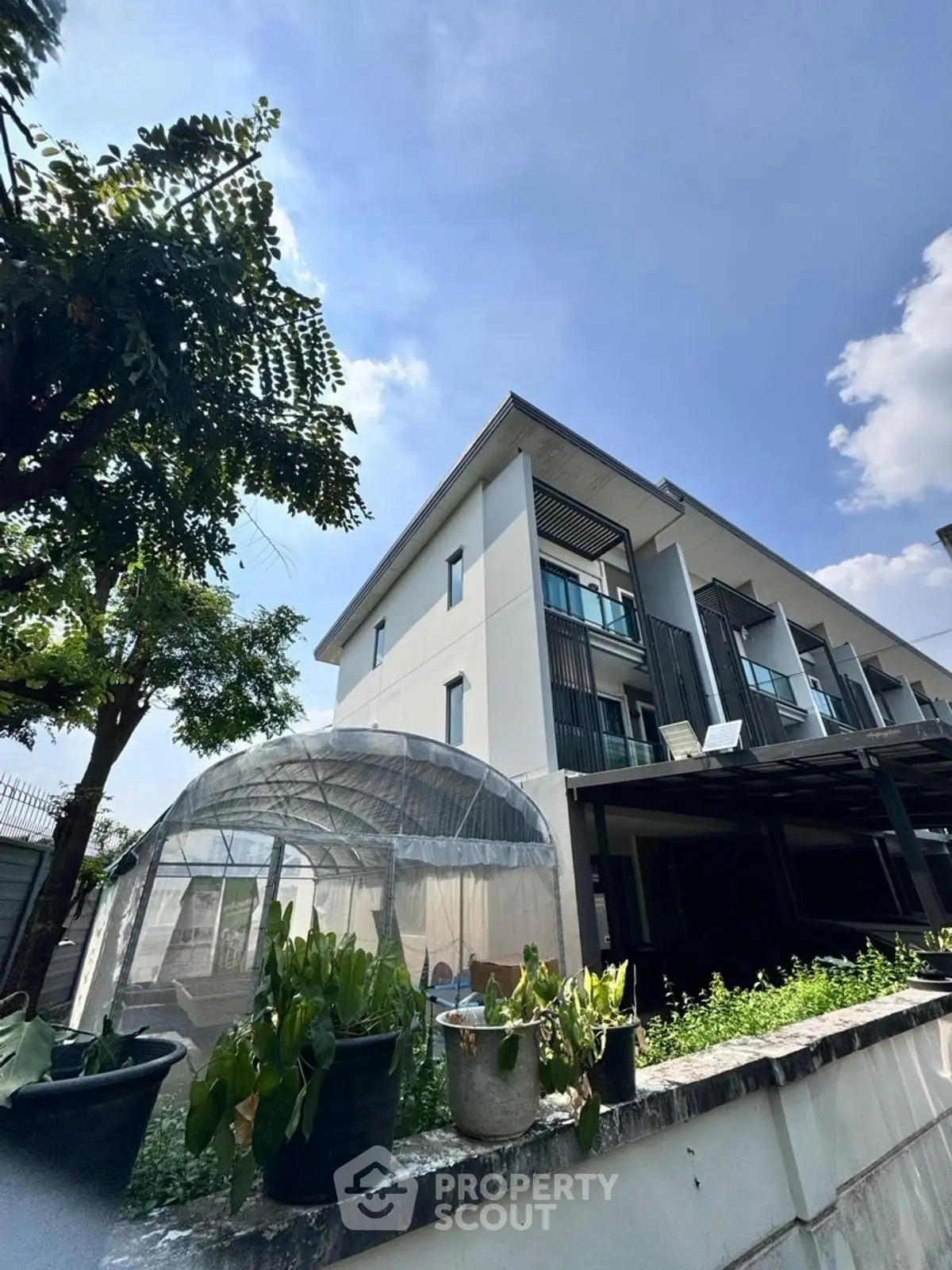 Modern townhouse exterior with garden and clear blue sky
