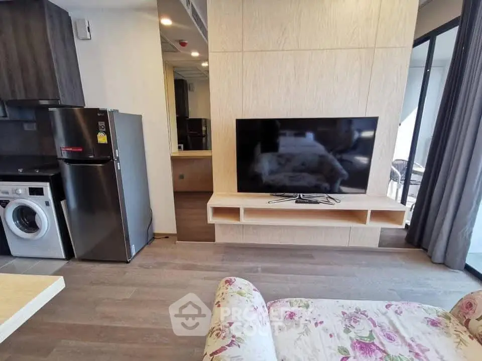Modern living room with stylish furniture, large TV, and open kitchen layout.