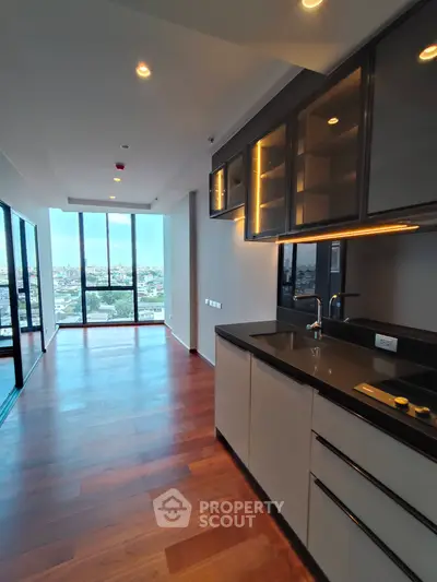 Modern open-layout kitchen with sleek cabinetry and expansive city view from large windows.