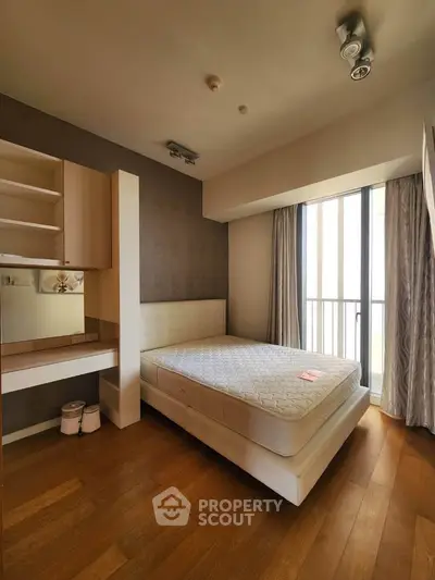 Spacious bedroom with natural light and modern furnishings in a stylish apartment.