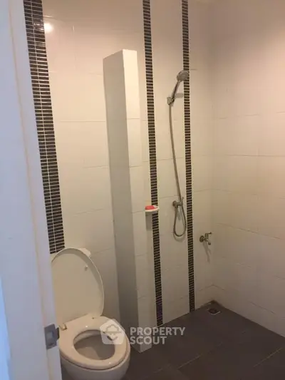 Modern bathroom with shower and toilet in sleek white tile design.