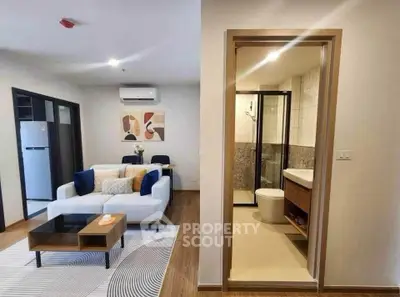 Modern living room with cozy seating and adjacent bathroom in stylish apartment.