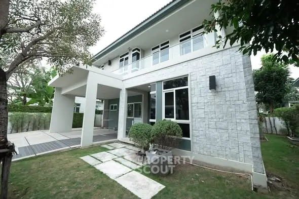 Modern two-story house with large windows and landscaped garden