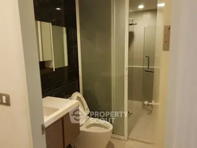 Modern bathroom with sleek design and glass shower enclosure in a contemporary apartment.