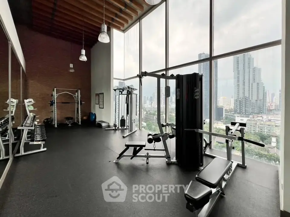 Spacious gym with modern equipment and stunning city view in luxury high-rise building.