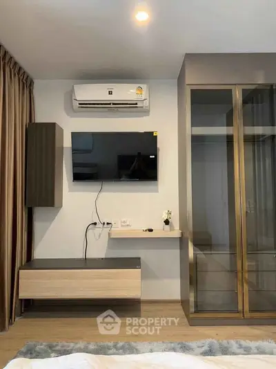 Modern bedroom with wall-mounted TV and air conditioning, featuring sleek storage solutions.