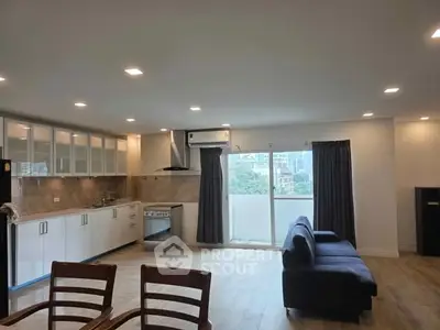 Spacious modern living room with open kitchen and balcony view.