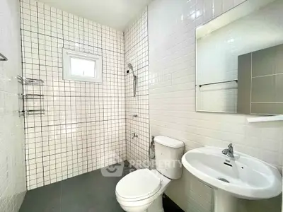 Modern bathroom with white tiled walls and sleek fixtures, featuring a compact window for natural light.