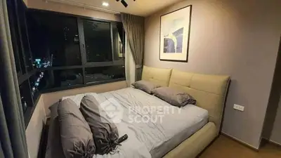 Cozy bedroom with city view, featuring a plush bed and modern decor, perfect for urban living.