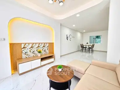 Modern living room with elegant decor and open dining area, featuring stylish furniture and ambient lighting.