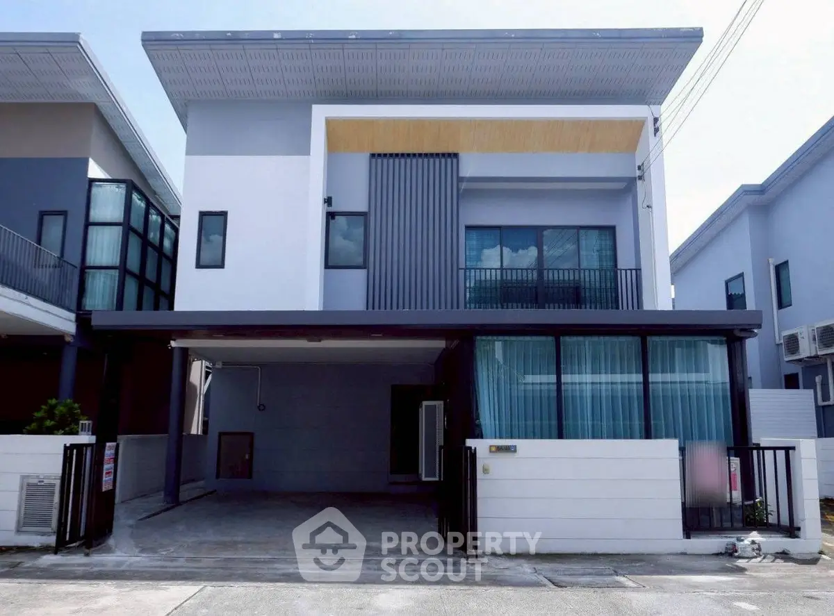 Modern two-story house with sleek design and spacious driveway in suburban neighborhood.