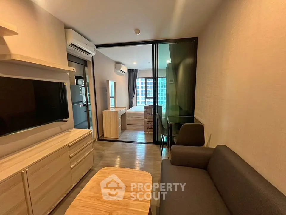 Modern apartment living room with sleek furniture and view into bedroom
