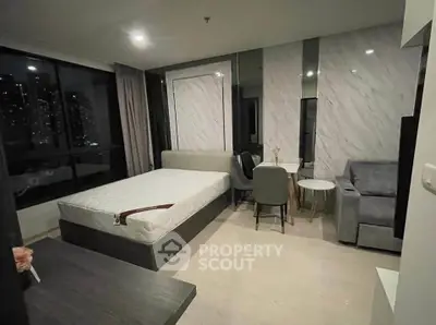 Modern studio apartment with stylish decor and city view, featuring a cozy bed and elegant seating area.
