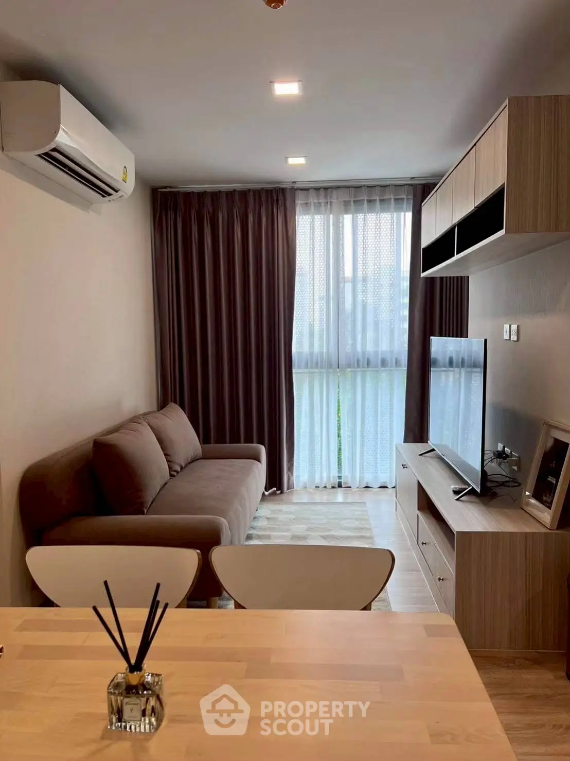 Modern living room with cozy sofa, flat-screen TV, and stylish decor in a well-lit apartment.