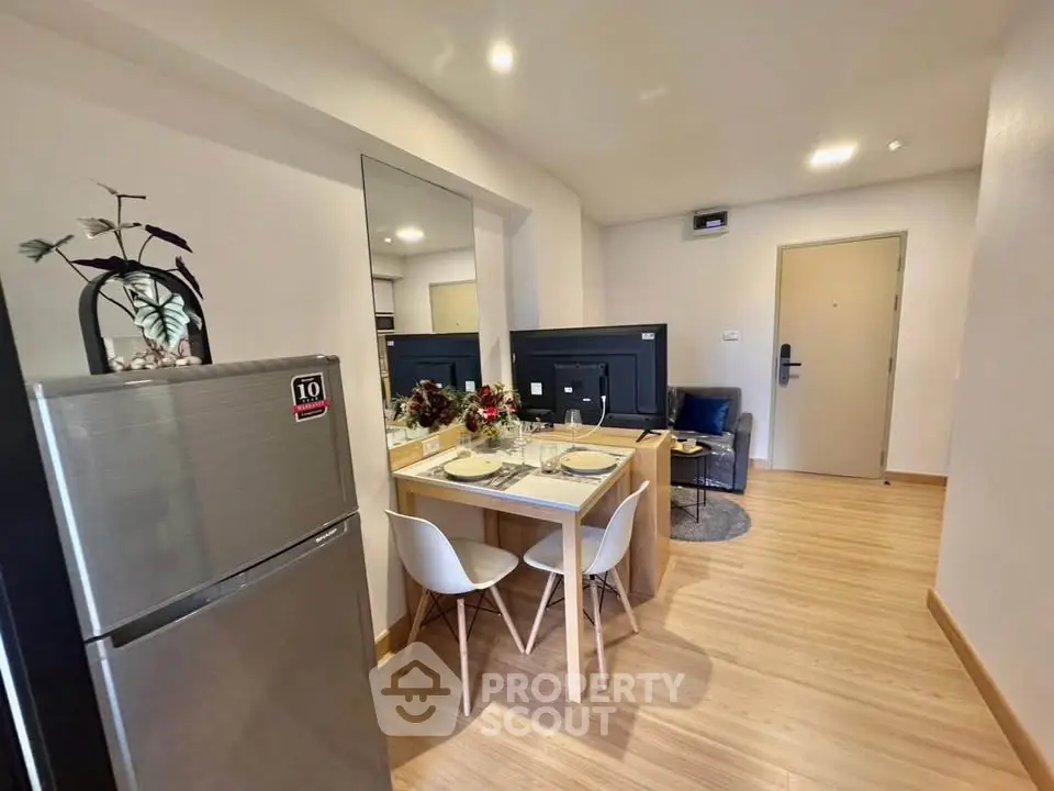 Modern apartment interior with dining area and living room, featuring sleek furniture and wooden flooring.