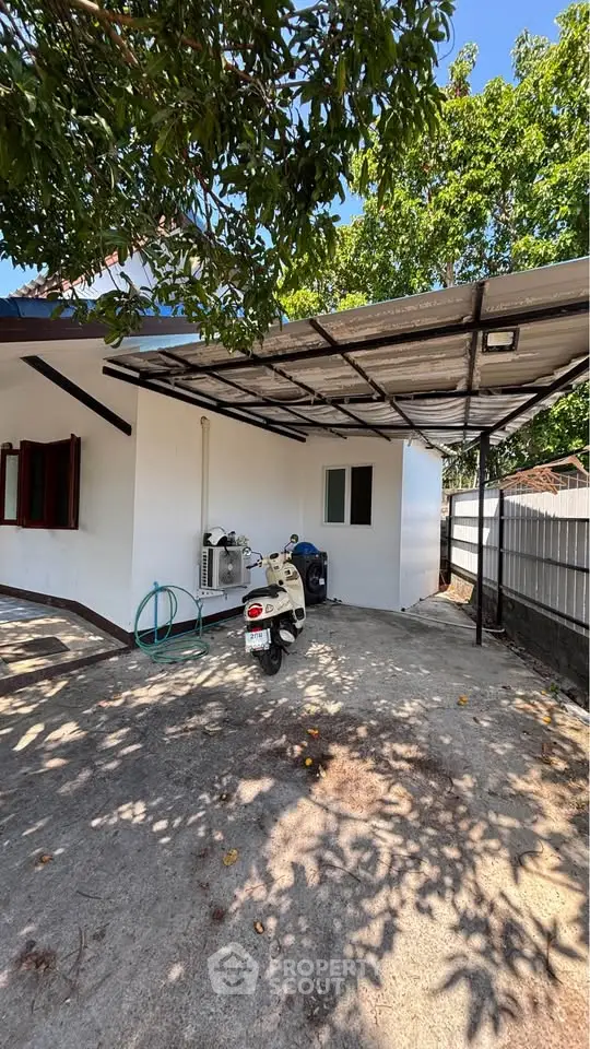 Charming house exterior with covered parking and lush greenery, perfect for serene living.