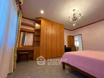 Spacious bedroom with elegant chandelier and ample storage in a cozy home.