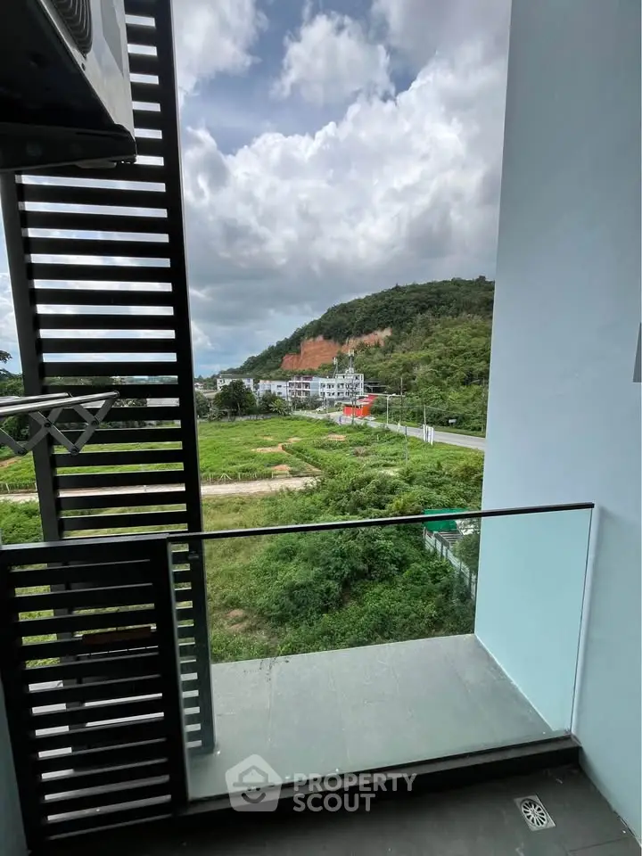 Stunning balcony view with lush greenery and distant hills, perfect for relaxation.