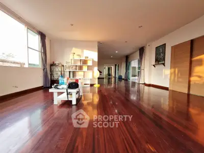 Spacious living room with polished wooden floors and ample natural light