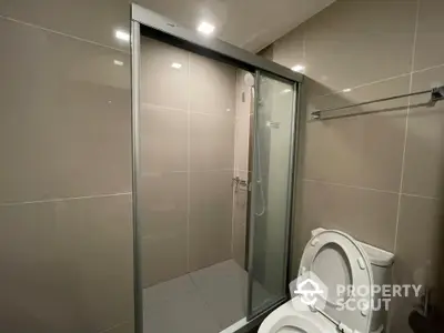 Modern bathroom with glass shower enclosure and sleek beige tiles, offering a clean and minimalist design.