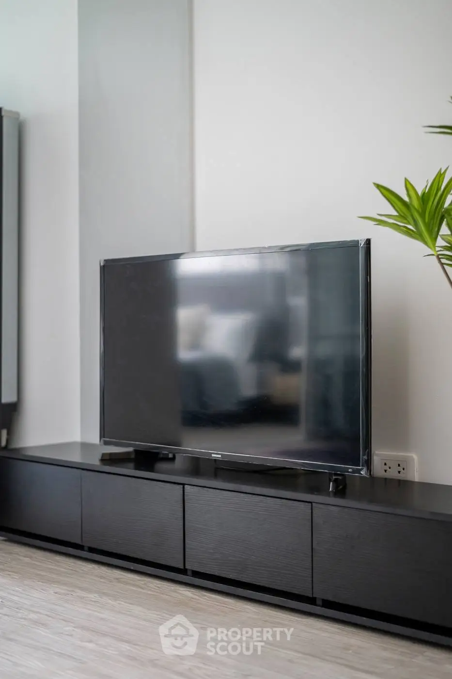 Modern living room with sleek black TV stand and large flat-screen TV.