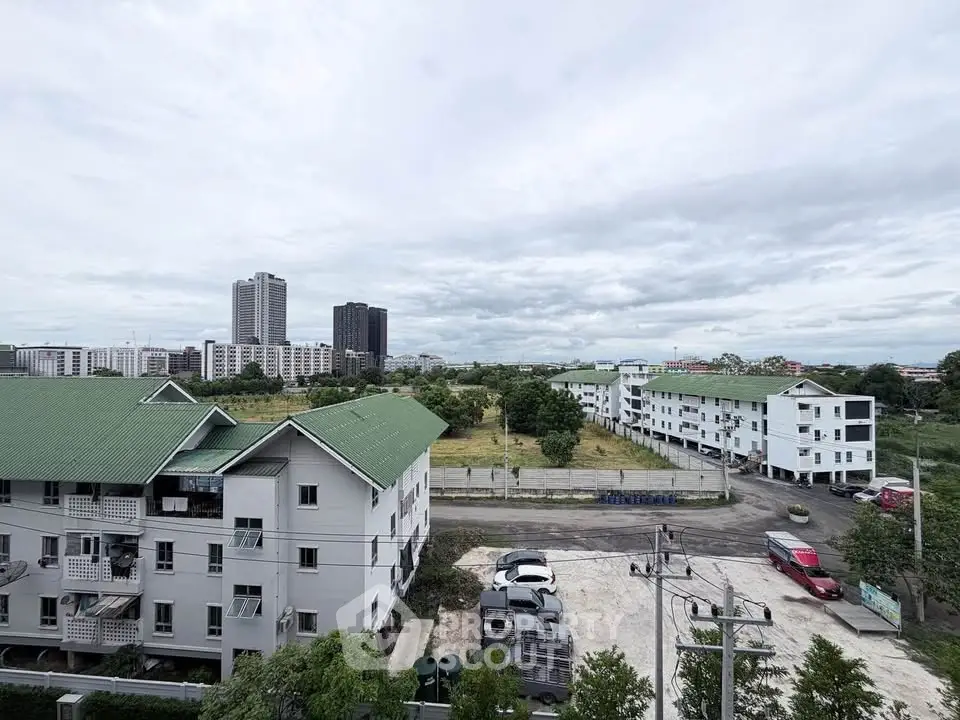 Panoramic view of residential buildings with green roofs and city skyline in the background.