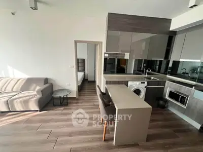 Modern open-plan living room with sleek kitchen and cozy seating area, perfect for urban living.