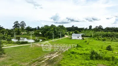 Scenic rural property with lush greenery and a small white house near a pond, ideal for nature lovers.